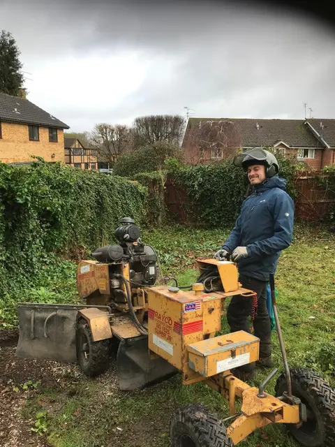 Operator with a stump grinder in a residential garden