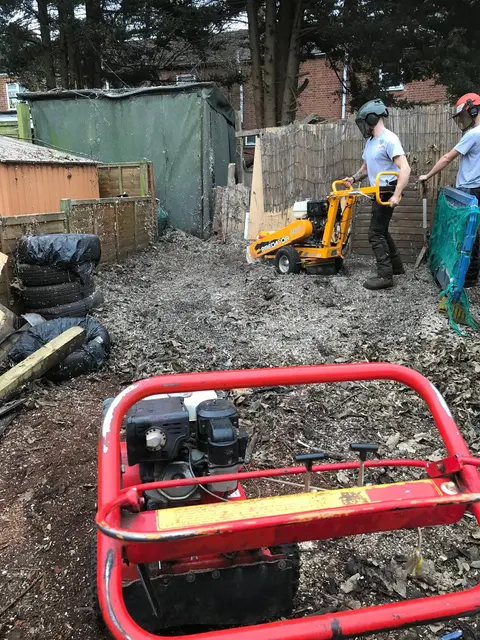 Two operators removing a stump in a back garden